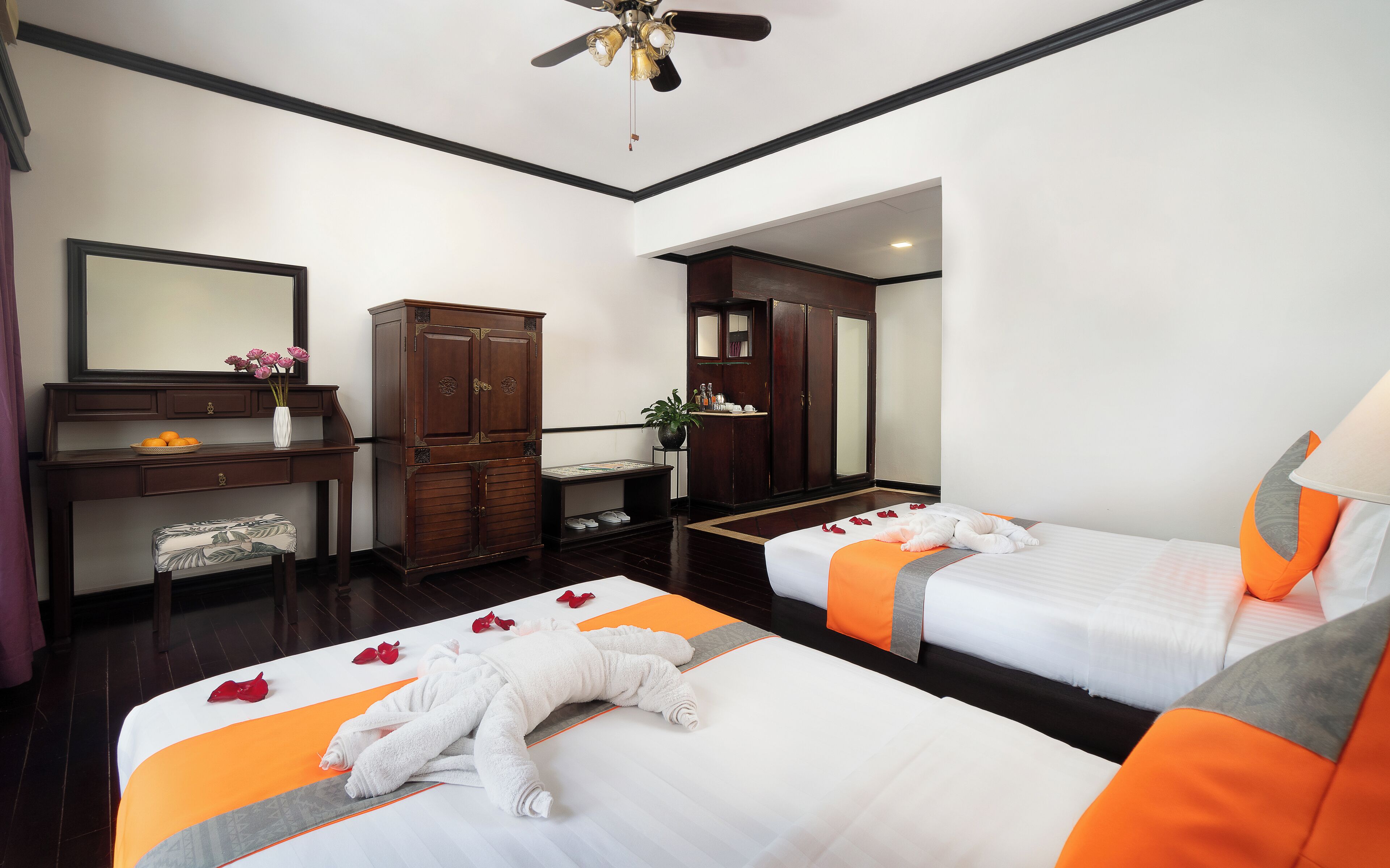 Habitación de hotel con dos camas, un escritorio, un armario y baño.