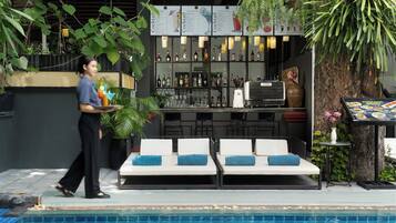 Ein Barbereich am Pool mit Liegestühlen, einer Theke voller Flaschen und einer Speisekarte.
