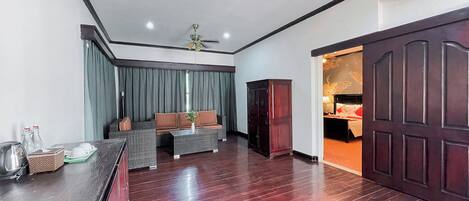 Habitación de hotel con piso de madera oscura, un sofá, una mesa de centro, un armario y una cama decorada con un corazón rojo.
