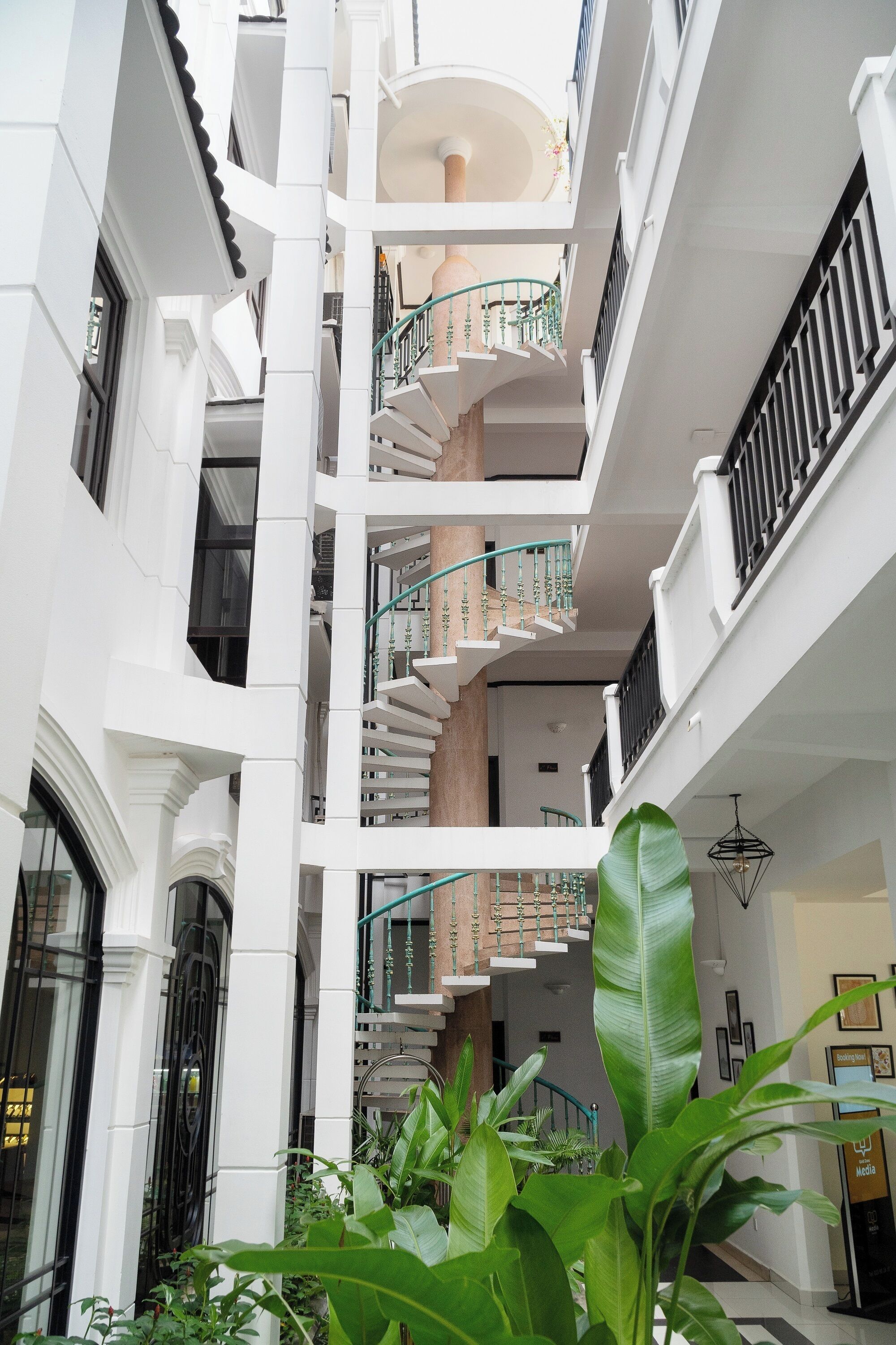 A multi-level interior with a central staircase, white walls, and balconies.