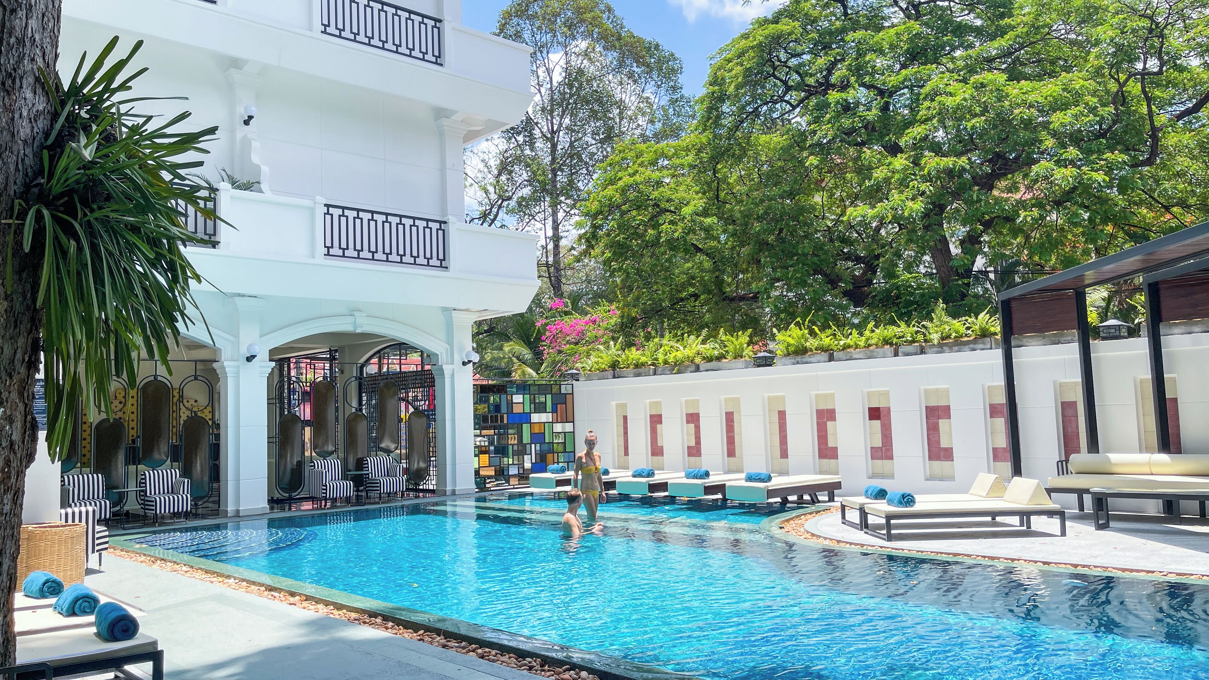 A pool area with lounge chairs and a covered seating area.