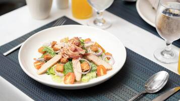A plate of salad with croutons, bacon, and cheese on a table with a napkin, fork, and spoon.