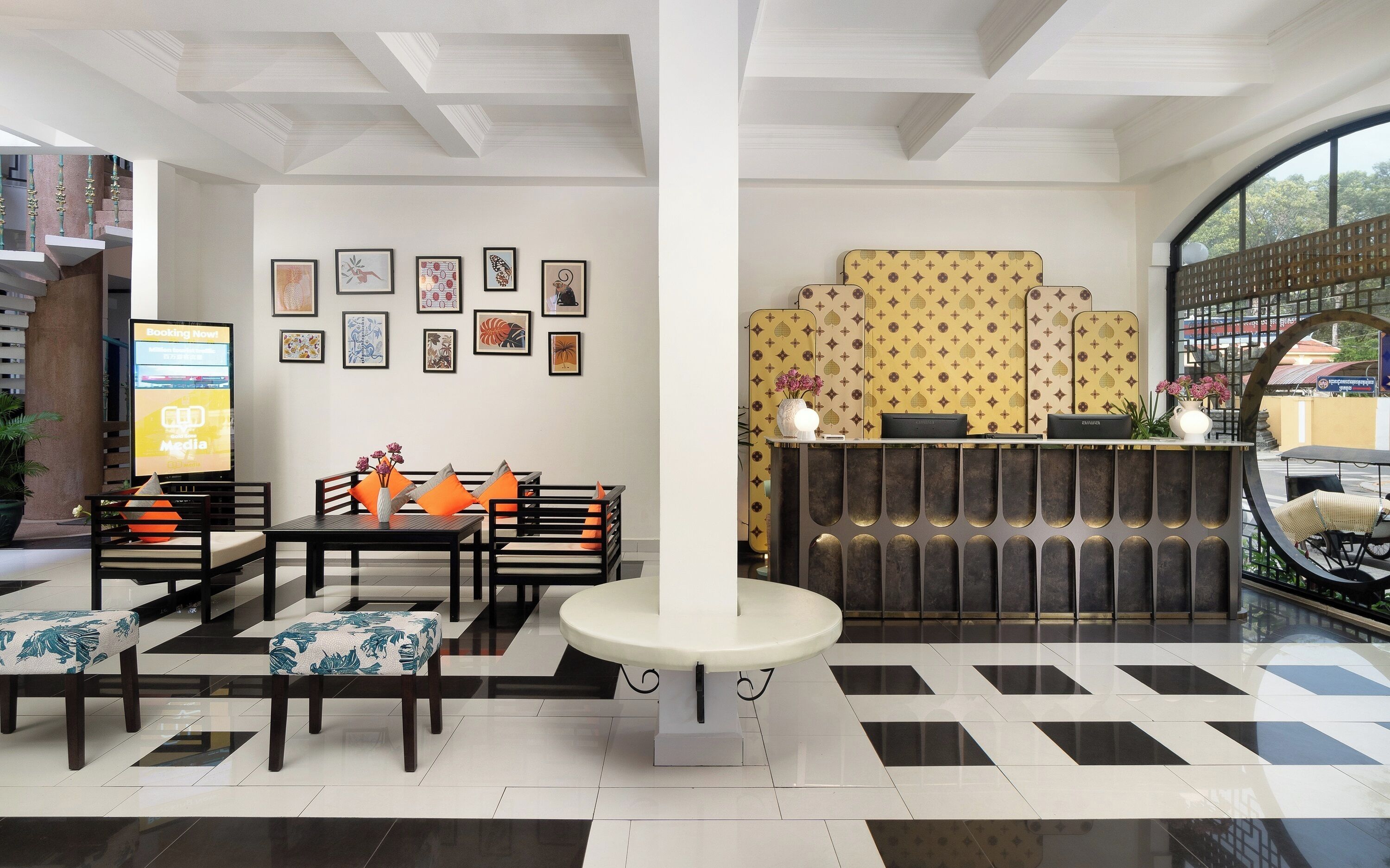 Un hall de hotel con mostrador de recepción, zona de estar y obras de arte en las paredes.