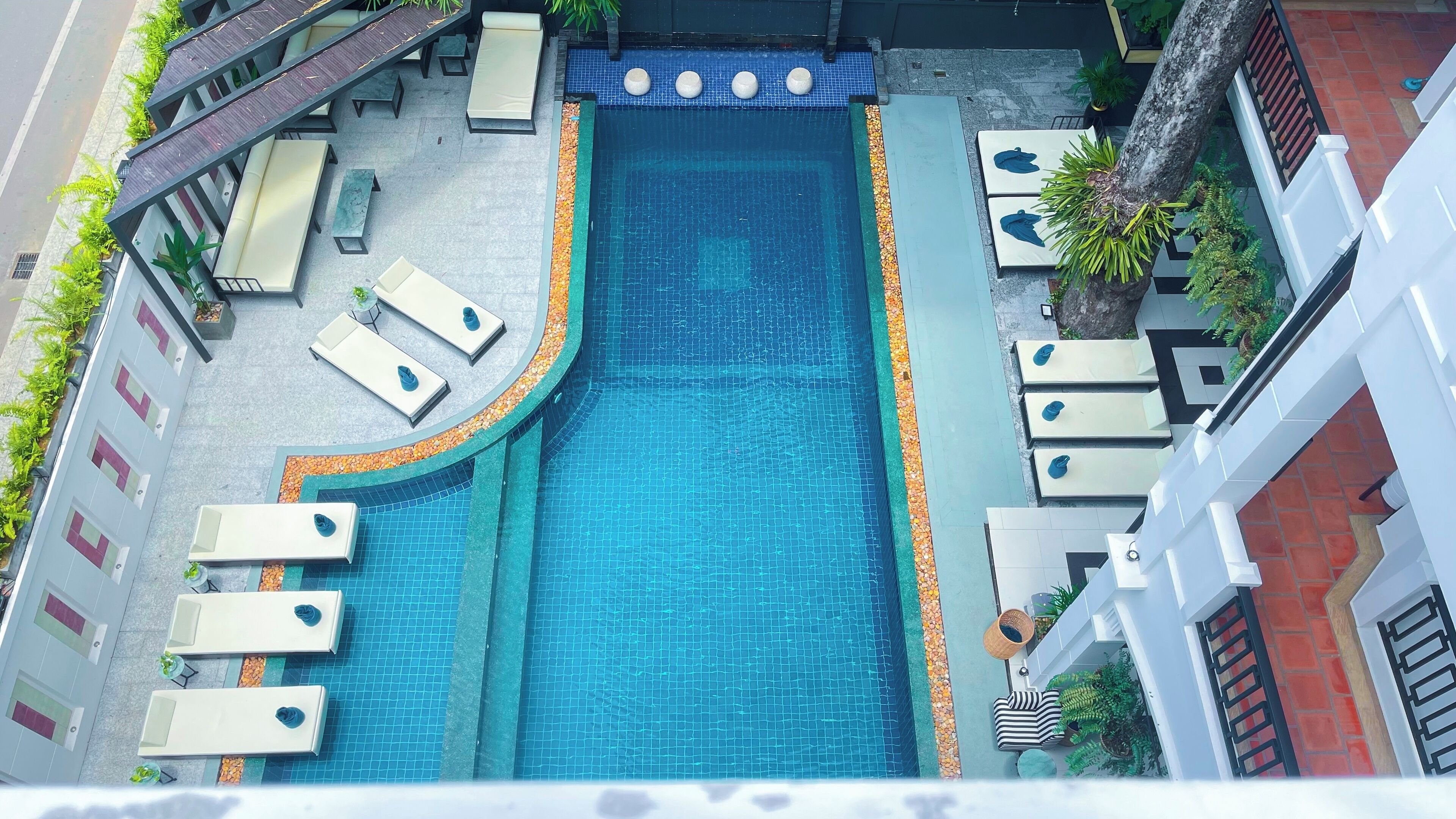 A rooftop pool with lounge chairs and a small waterfall feature.