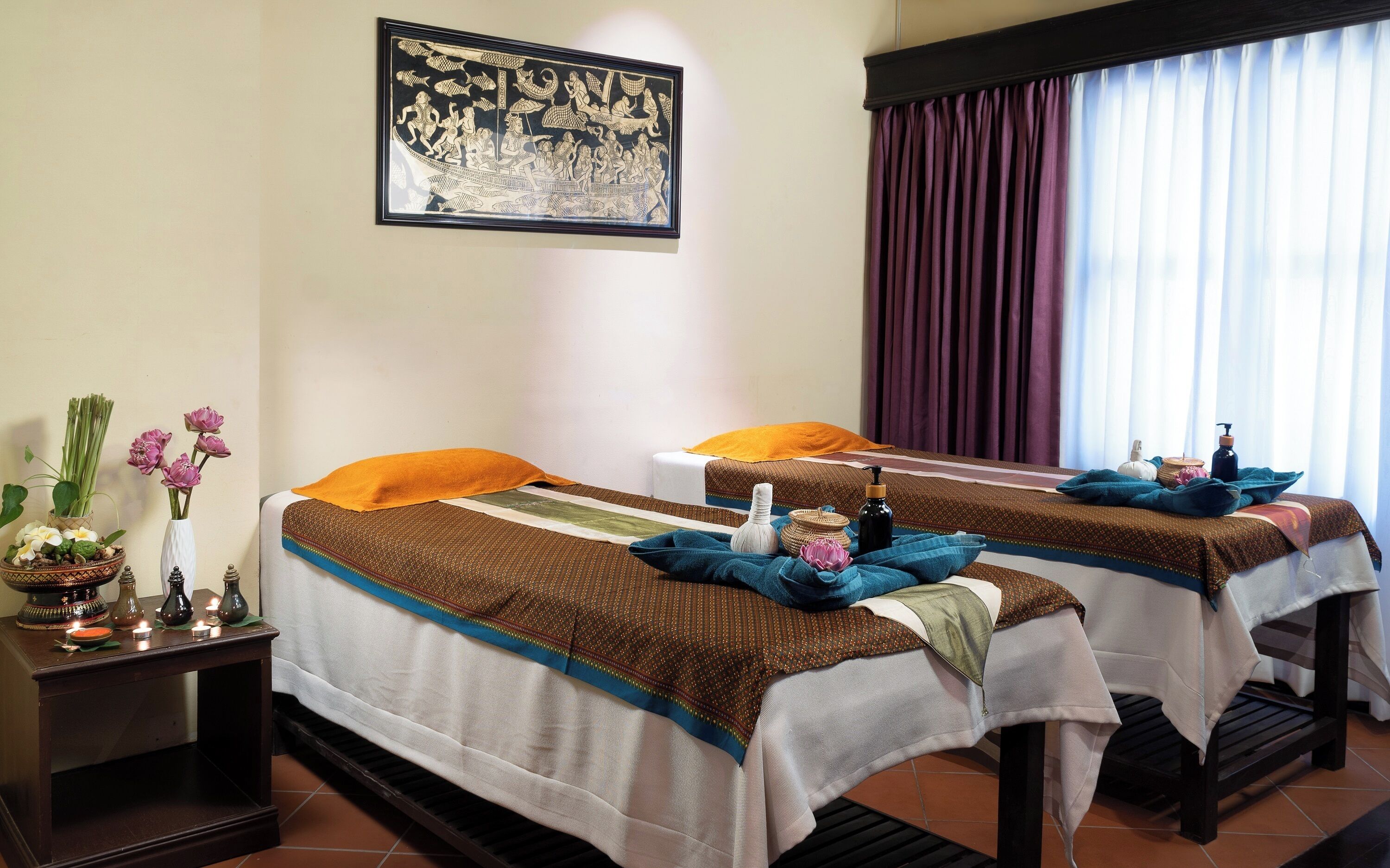 A room with two beds, a wall-mounted picture, and a window with curtains.