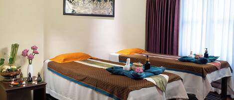 A room with two beds, a wall-mounted picture, and a window with curtains.