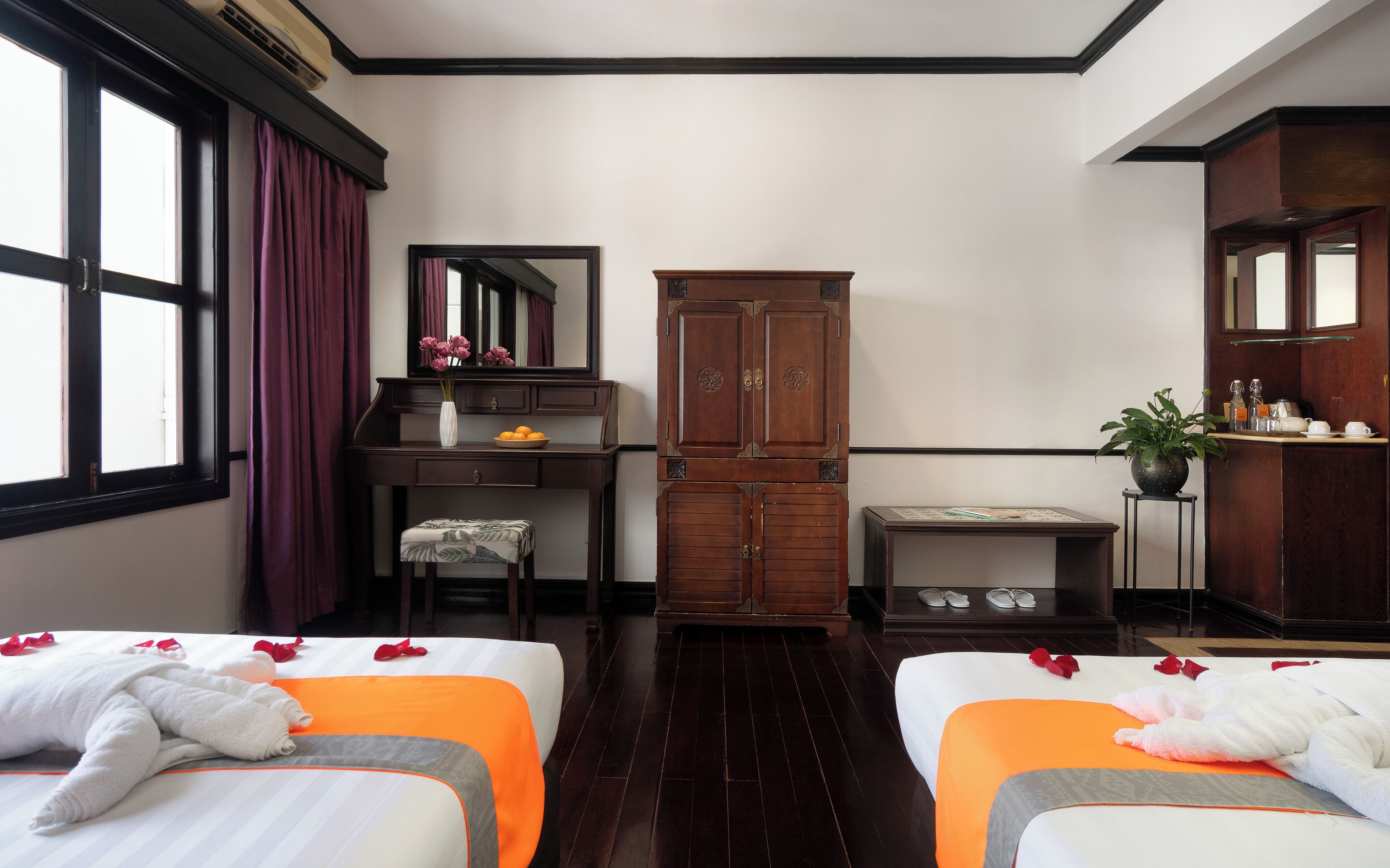 A hotel room with two beds, a desk, a wardrobe, and a bathroom.