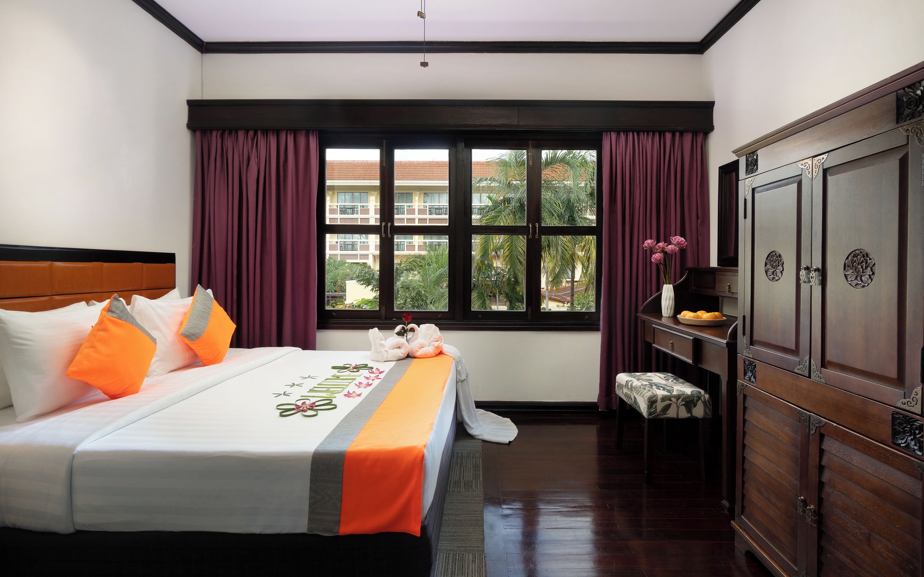 Una habitación de hotel con una cama, un escritorio, un armario y una ventana con cortinas.