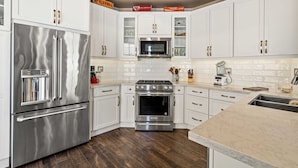 A modern kitchen with white cabinets, stainless steel appliances, and a marble countertop. - Charming 3-bedroom furnished, home with WiFi, AC in Spanish Hills Camarillo (Camarillo)