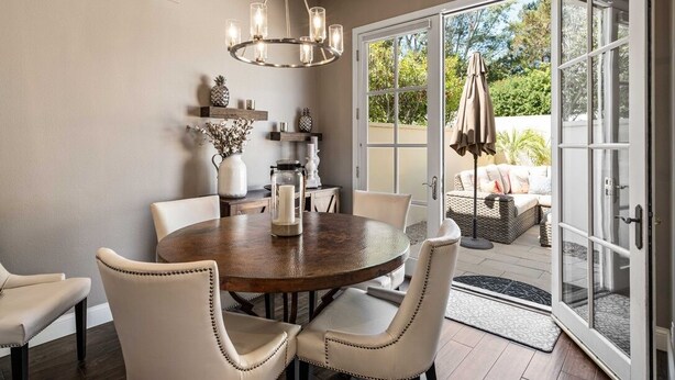 A dining area with a round table, chairs, a chandelier, and a view of the outdoors through glass doors. - Charming 3-bedroom furnished, home with WiFi, AC in Spanish Hills Camarillo (Camarillo)