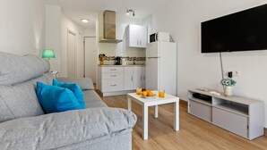 A modern living room with a grey sofa, a small white table with drinks, and a kitchen in the background. - Torre Copenhague - Terrace, Swimming Pool, Bechfront (Torremolinos)