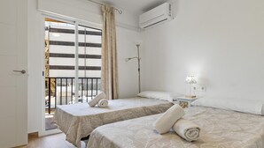 A hotel room with two beds, a balcony, an air conditioning unit, and a bedside table with a lamp. - Torre Copenhague - Terrace, Swimming Pool, Bechfront (Torremolinos)