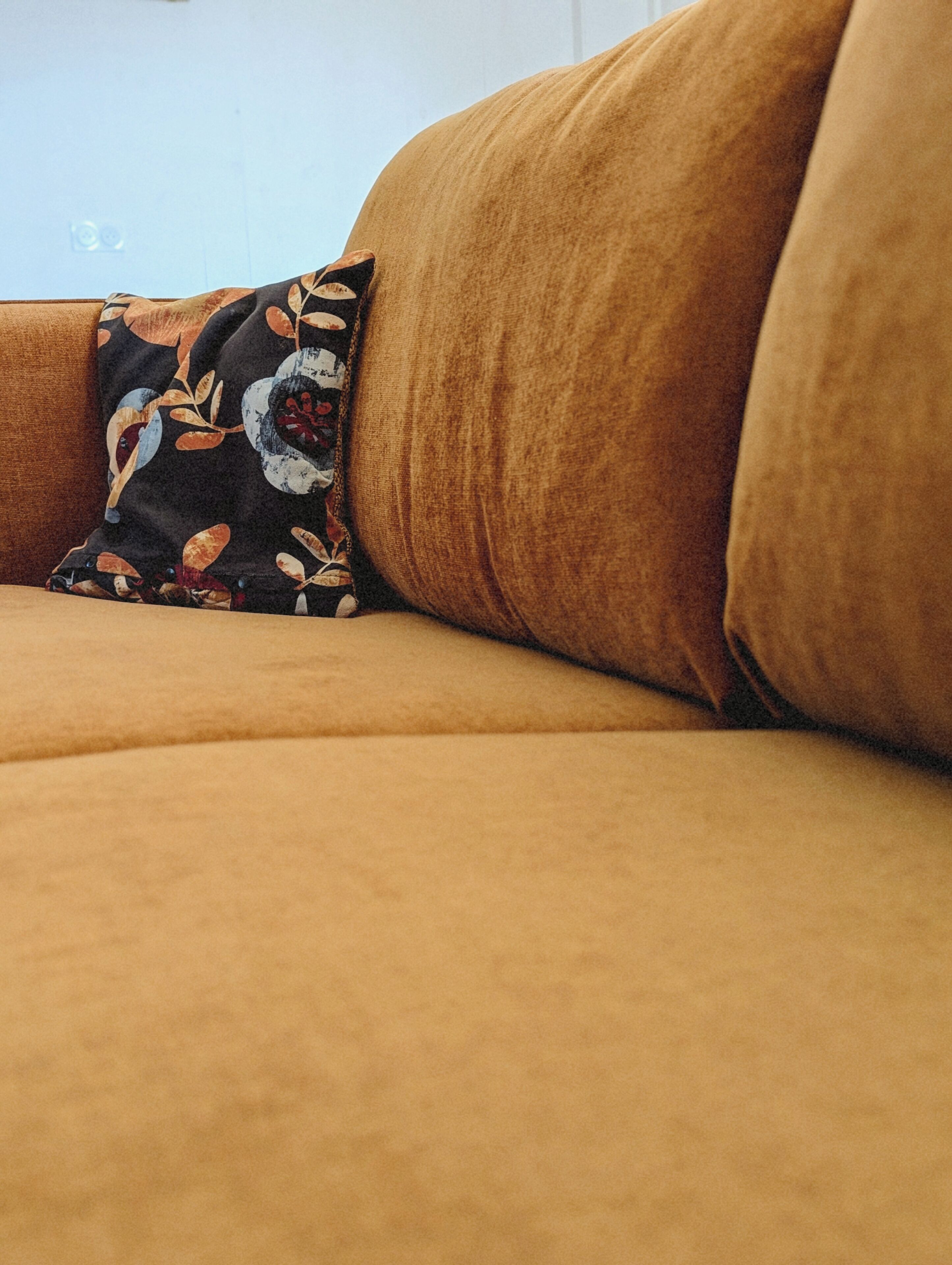 Ein Detailaufnahme eines braunen Sofas mit einem gemusterten Kissen.