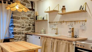Una cocina con una mesa y sillas de madera, una pared de piedra y una lámpara colgante.