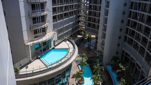 A multi-level hotel with a central courtyard featuring a swimming pool, surrounded by balconies and potted plants.