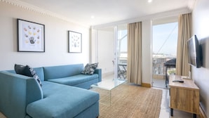 A modern living room with a blue sofa, a glass coffee table, and a TV on a wooden stand.