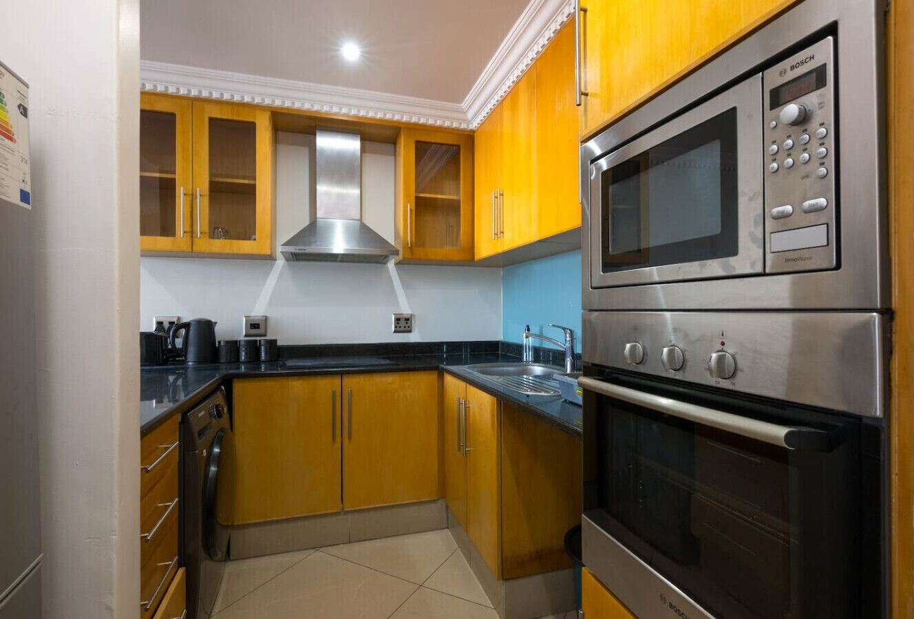 A kitchen with wooden cabinets, a stainless steel oven, and a microwave.