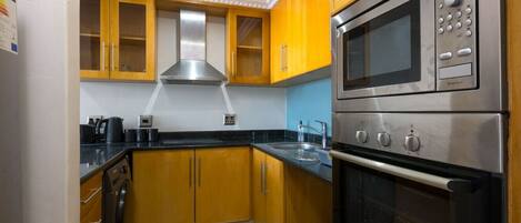 A kitchen with wooden cabinets, a stainless steel oven, and a microwave.