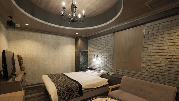 Una habitación de hotel moderna con una cama, una mesa redonda, un sofá y una pared de ladrillo.