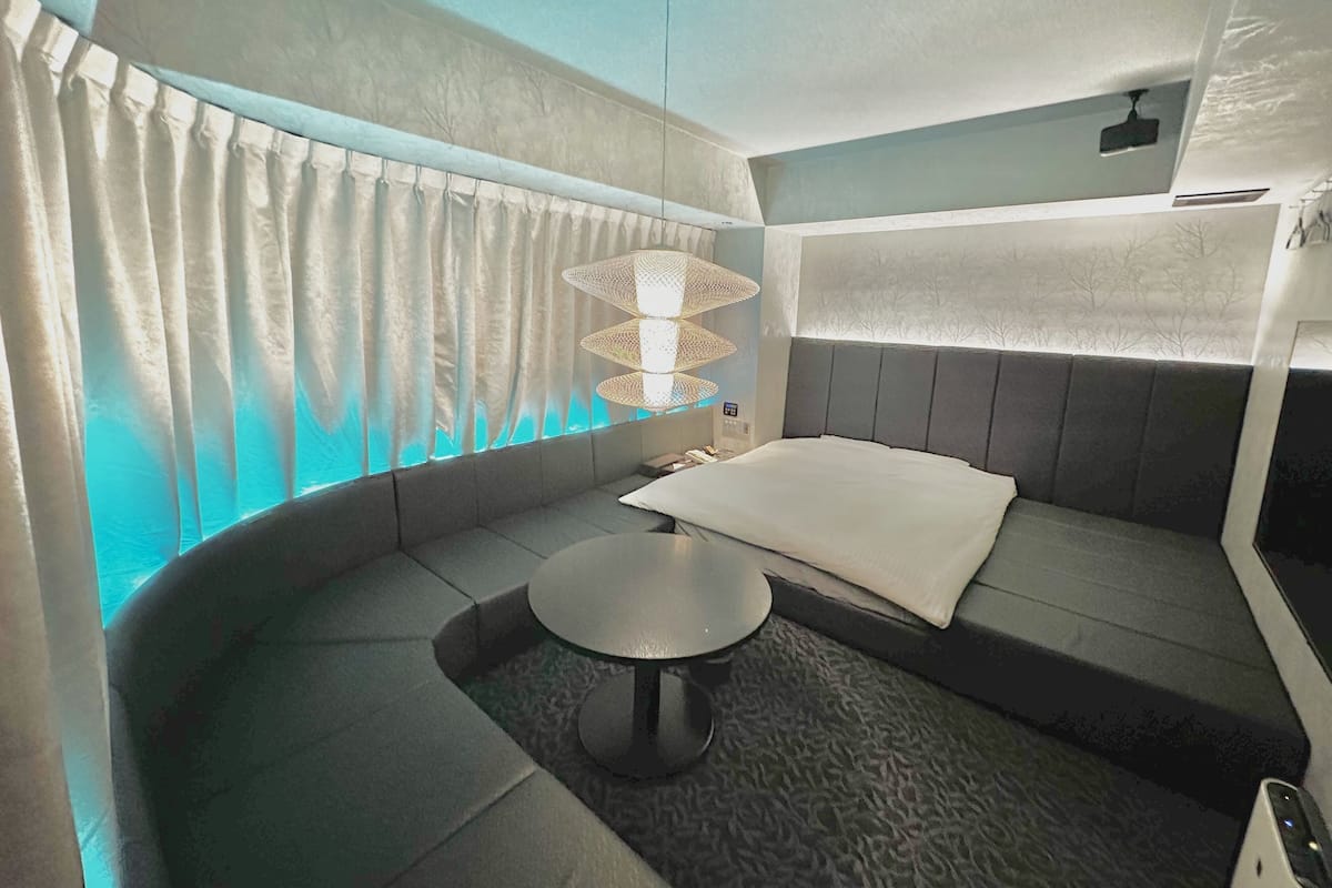 A modern room with a curved sofa, a round table, and a unique hanging light fixture.