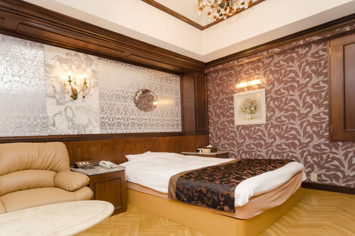 A hotel room with a sofa, a bed, a nightstand, and a mirror.
