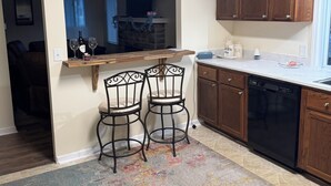 Una cocina con armarios de madera, lavavajillas integrado y un amplio ventanal.