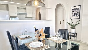 Un espace repas moderne avec une table en verre, des chaises noires et un élément décoratif central.
