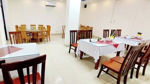 A dining area with multiple tables and chairs, arranged in a spacious room with white walls and tiled flooring. - SVFU Ha Noi (Hanoi)