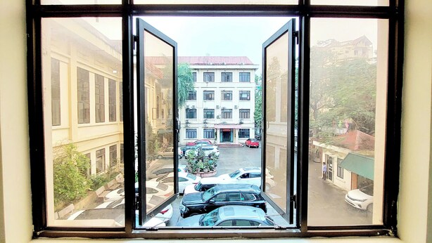 A view through a window with a street scene, including parked cars and buildings. - SVFU Ha Noi (Hanoi)