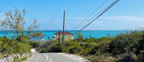 Eine Küstenstraße mit freiem Blick auf das Meer und einem Gebäude in der Ferne.
