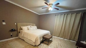 A bedroom with a bed, a ceiling fan, a bedside table, a nightstand, and a window with curtains. - L&L Cozy Stuido Inn Studio unit Exuma (Exuma)