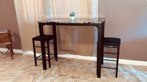 A small table with two black chairs, a potted plant on the table, and a curtain in the background. - L&L Cozy Stuido Inn Studio unit Exuma (Exuma)