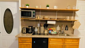 A compact kitchen with a built-in dishwasher, a microwave, and a coffee maker. There are wooden cabinets and a countertop with various kitchen items. - L&L Cozy Stuido Inn Studio unit Exuma (Exuma)