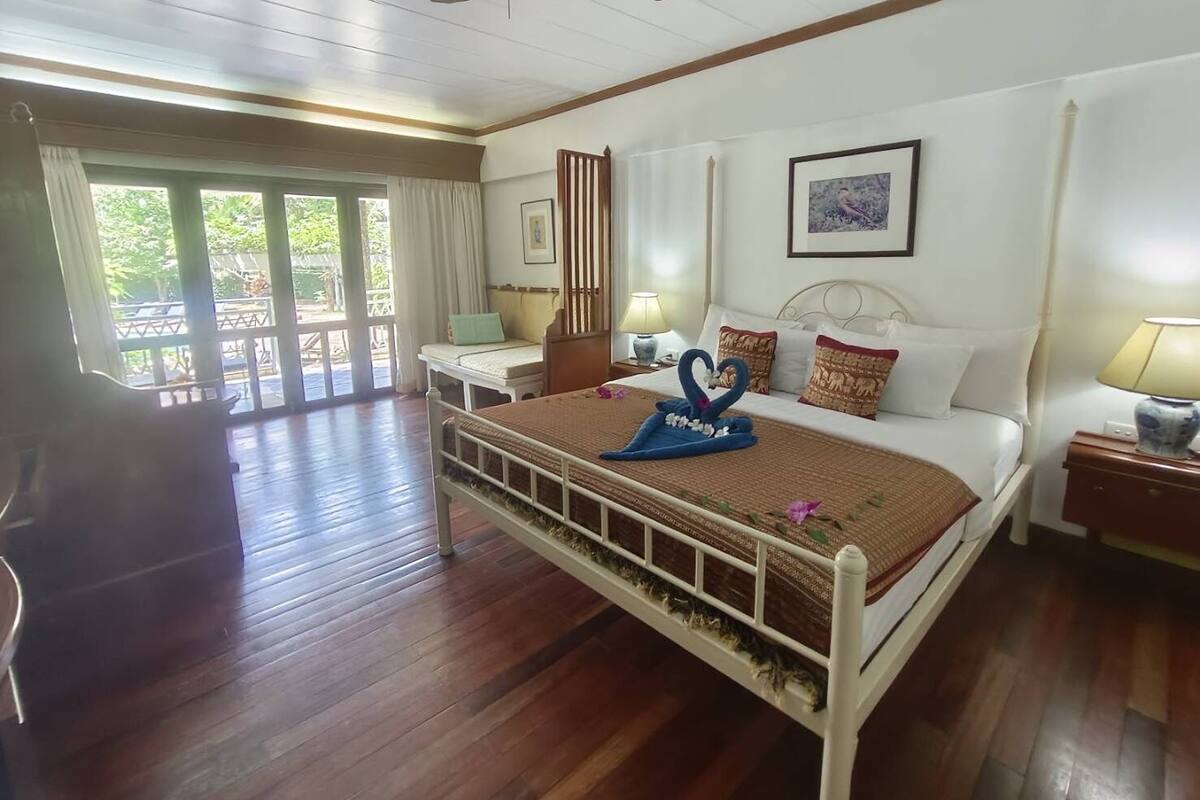 A bedroom with a bed, bedside tables, a ceiling fan, and a view of the outdoors.