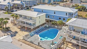 Un hotel frente a la playa con piscina, varios balcones y vista al océano.