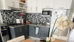 Une cuisine moderne avec des meubles blancs, un four à micro-ondes et un évier. On y trouve deux chaises et une table avec des sets de table.