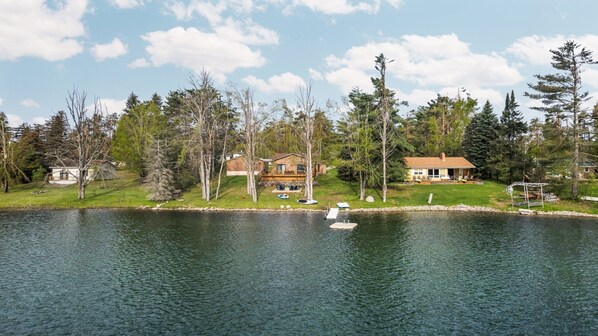 Propiedad junto al lago con varias casas, un muelle y un bote.