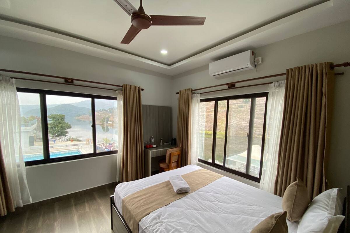 Une chambre d’hôtel avec un lit, un bureau et une vue sur une piscine et des montagnes.