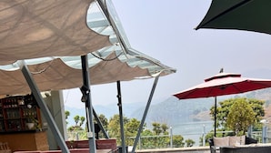 Ein Außenbereich mit Tischen, Stühlen und einer Bar, mit Blick auf die Berge.