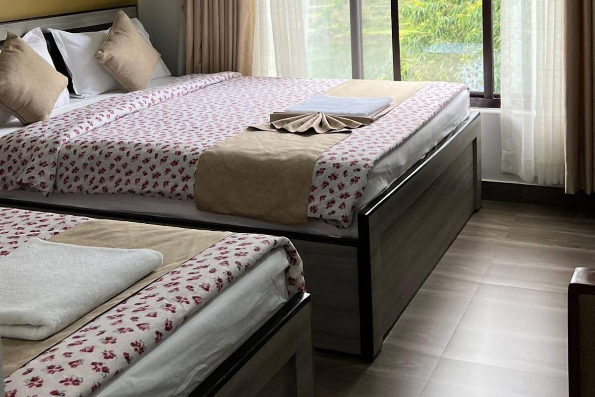 Une chambre d’hôtel avec deux lits, un ventilateur de plafond, un appareil de climatisation et une grande fenêtre avec des rideaux.