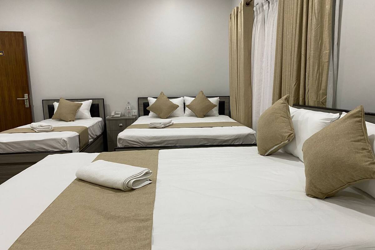 Une chambre d’hôtel avec deux lits simples, un grand lit et une salle de bain.
