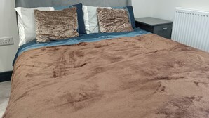 Ein Bett mit brauner Decke, zwei Kissen und einer blauen Bettwäsche.