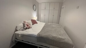 Een slaapkamer met een bed, een bedlampje, een kledingkast en een hanglamp.