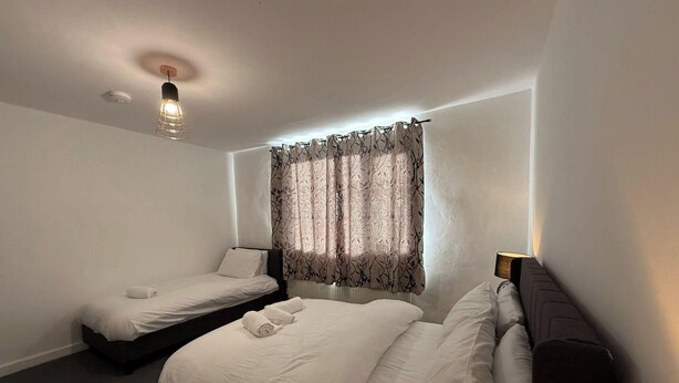 Ein Hotelzimmer mit zwei Betten, einer Deckenleuchte und einem Fenster mit Vorhängen.