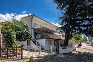 Ein zweistöckiges Gebäude mit Balkon, Treppe und geschlossenem Eingang.
