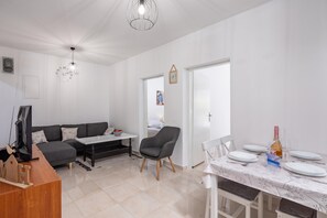A modern living room with a sofa, a dining table set for two, and a television. - Sea View Apartment Terazza Grande, Selce, Croatia (Selce)