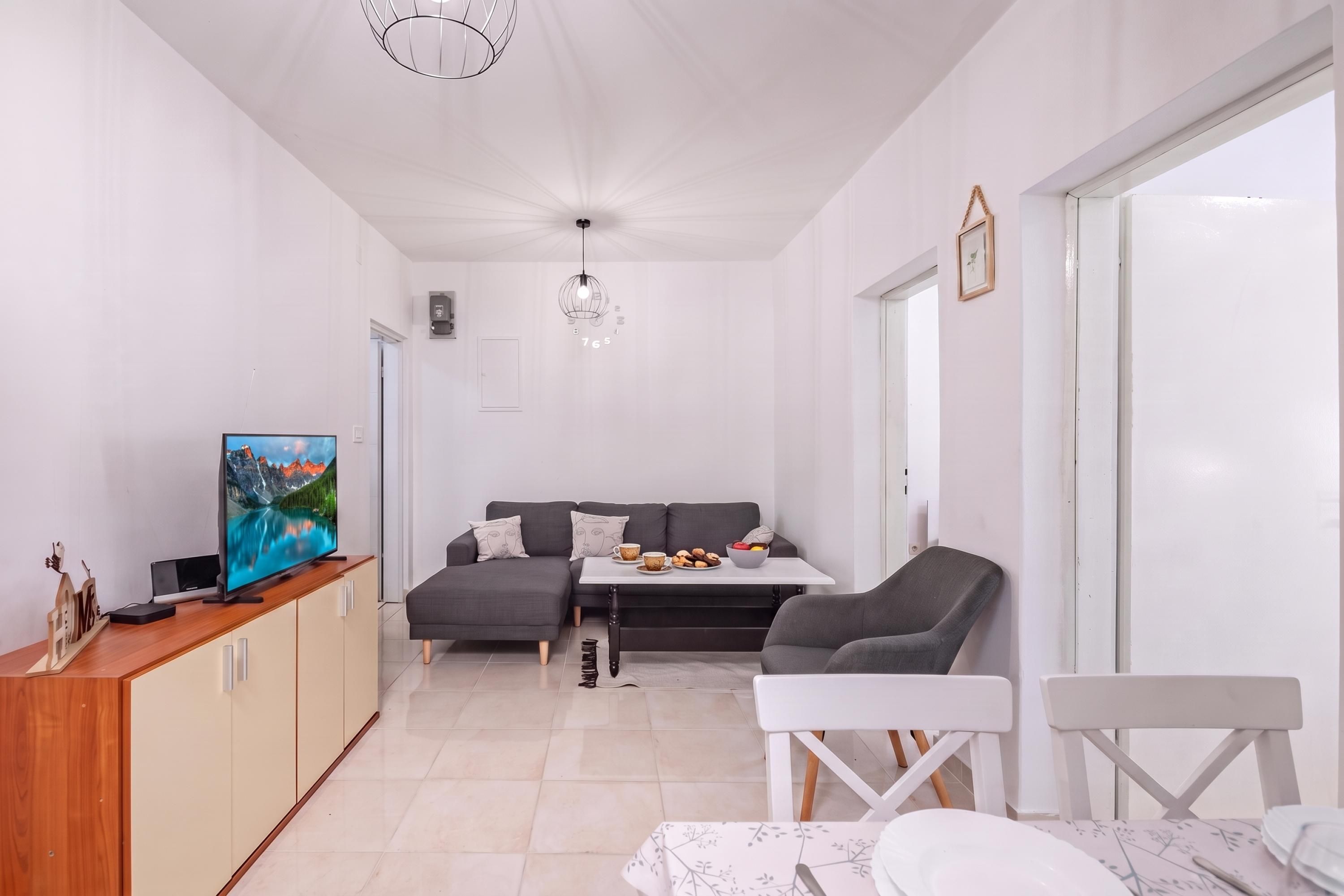 Una sala moderna con televisión, sofá, mesa de comedor y sillas.