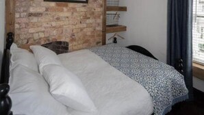 A bed with white bedding, a brick wall, and a window with curtains.