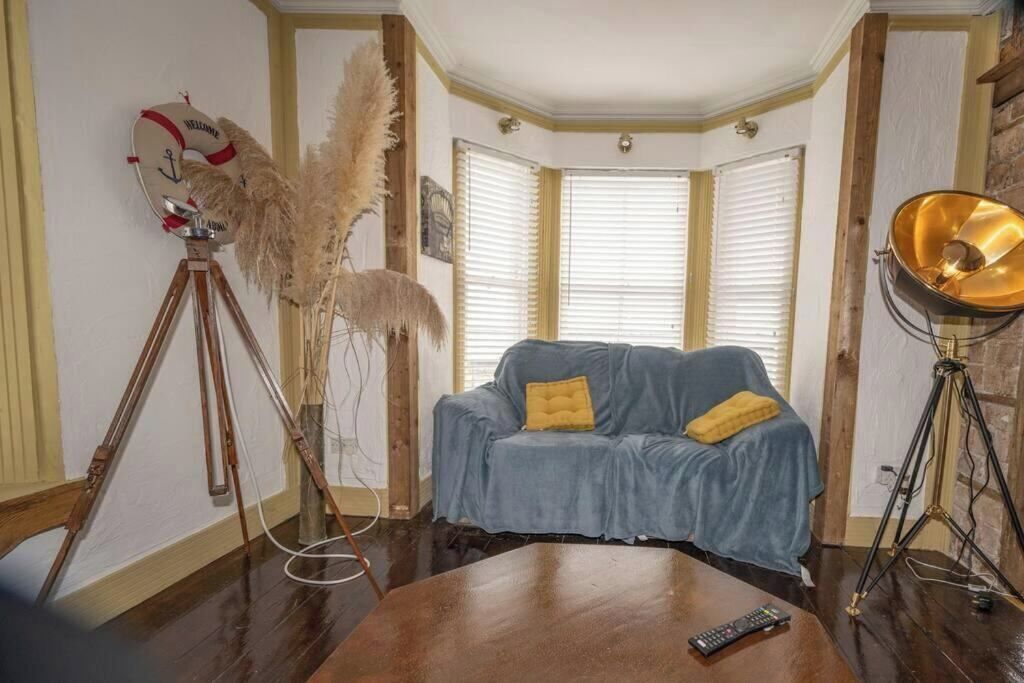 A cozy living room with a blue sofa, a wooden coffee table, a tripod, and a vintage lamp.