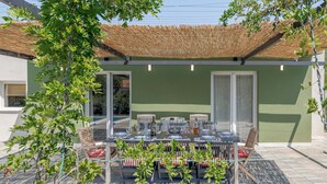 A dining area with a table set for four, surrounded by chairs, under a thatched roof.